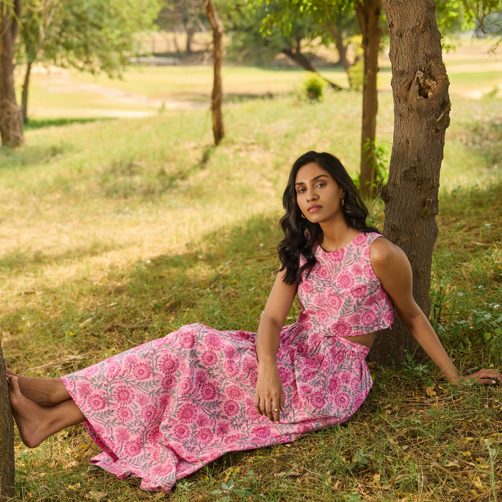 Woman in a pink floral dress sitting under a tree in a park wearing a pink outfit. Skirt Set